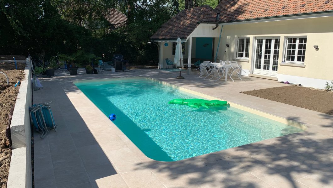 Piscine extérieure dans un jardin avec terrasse.