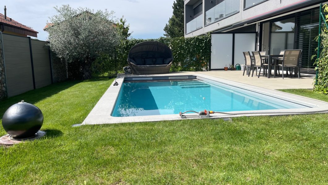 Piscine moderne avec terrasse et mobilier extérieur.