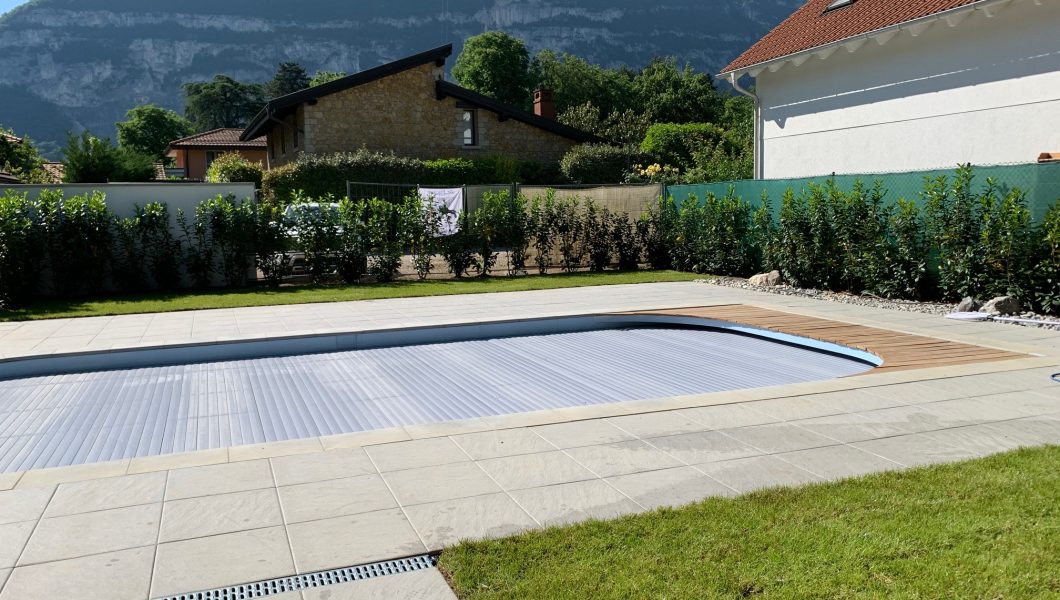 Jardin avec piscine couverte et montagnes en arrière-plan.