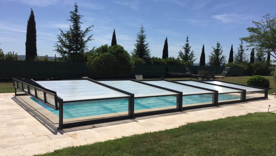Piscine couverte dans un jardin ensoleillé.
