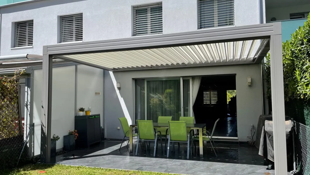 Terrasse avec pergola moderne, chaises et table vertes.