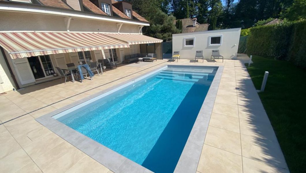 Piscine extérieure moderne avec terrasse et chaises longues.